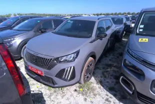 Peugeot 2008 gris clair vue 3/4 avant droit, avec calandre noire et feux LED à griffes distinctifs.