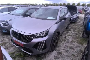 Peugeot 2008 gris clair vue 3/4 avant droit, calandre noire avec marquage vertical et feux LED griffés.