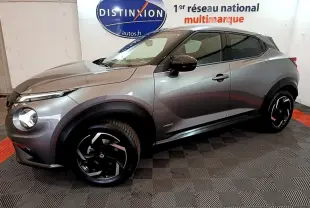 Nissan Juke Hybrid gris foncé vue de profil côté gauche dans un showroom avec jantes noires distinctives.