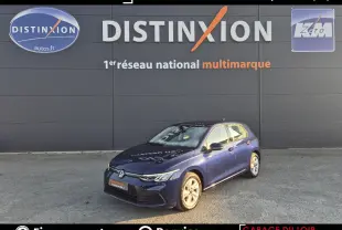 Volkswagen Golf bleu vue 3/4 avant droit, avec phares LED et jantes alliage visibles, stationnée devant un mur gris.