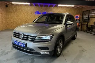 Vue 3/4 avant d'un Volkswagen Tiguan gris 2017 avec phares allumés dans un garage au sol béton.