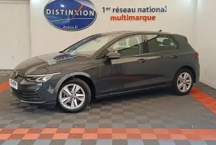 Profil droit d'une Volkswagen Golf gris foncé 2022 garée en intérieur sur sol à damier gris et rouge.