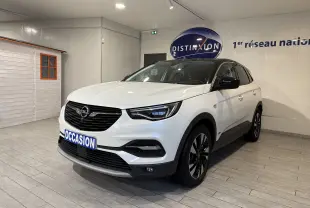 Vue 3/4 avant d’un Opel Grandland X blanc hybride rechargeable, avec jantes noires et toit noir dans un showroom.