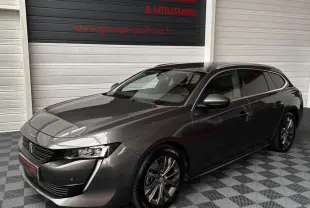 Peugeot 508 gris foncé vue 3/4 avant droit, avec jantes alliage et calandre noire brillante.
