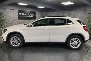 Profil droit d'un Mercedes GLA 180 Inspiration blanc, avec jantes alliage 17 pouces et poignées couleur carrosserie.