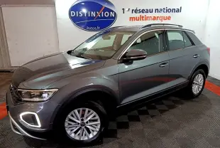 Vue 3/4 avant droit d'un Volkswagen T-Roc gris foncé avec feux LED et jantes alliage en intérieur showroom.