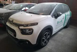 Vue 3/4 avant d'une Citroën C3 blanche avec décor vert et jantes noires dans un garage sombre