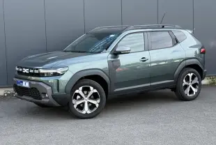 Vue 3/4 avant du Dacia Duster 2026 vert cèdre avec jantes alliage diamantées et barres de toit noires.