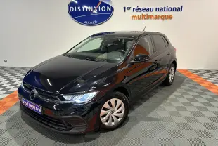 Volkswagen Polo noire vue en 3/4 avant droit, avec phares allumés dans un showroom lumineux.