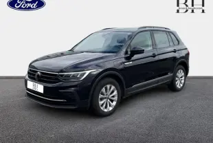 Volkswagen Tiguan 1.4 eHybrid noir nacré en 3/4 avant droit, avec jantes alu et barres de toit visibles.
