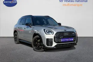 Vue 3/4 avant d'un MINI Countryman C 170ch JCW DKG7 argenté avec jantes noires et toit noir, sur fond neutre.
