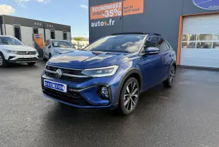 Volkswagen Taigo bleu récif métallisé en 3/4 avant droit avec jantes alliage noires brillantes sur parking.