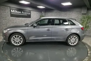 Audi A3 Sportback gris vue de profil côté gauche dans un showroom avec jantes aluminium 17 pouces.