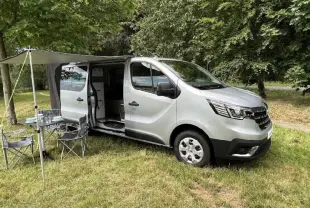 Renault Trafic Fourgon gris vue 3/4 avant droit avec porte latérale ouverte et auvent déployé en extérieur.