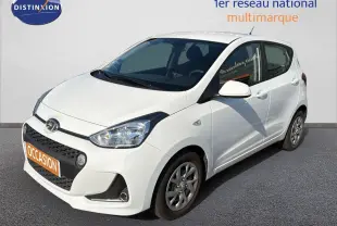 Vue 3/4 avant droite d'une Hyundai i10 blanche de 2018 avec calandre noire et jantes alliage.