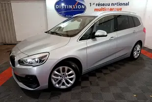 BMW Série 2 Gran Tourer 218d gris clair vue 3/4 avant droit avec phares LED allumés en intérieur showroom.