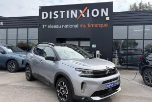Vue 3/4 avant droit d’un Citroën C5 Aircross gris métal avec toit noir et jantes alliage bi-ton devant un concessionnaire.