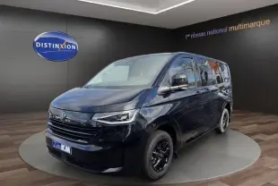 Vue 3/4 avant droit d’un Volkswagen Transporter noir 2026 avec jantes noires et phares LED, en showroom.