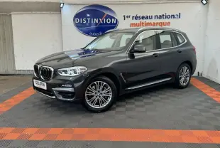 BMW X3 xDrive30d gris foncé vu de 3/4 avant droit dans un showroom avec sol noir et orange.