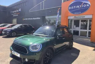 Vue 3/4 avant droite d'une MINI Countryman Cooper D 2018 en British Racing Green avec jantes noires devant un concessionnaire.