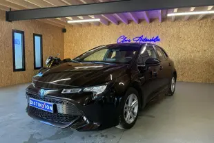 Toyota Corolla 1.8 122 Dynamic noire vue 3/4 avant droit en intérieur avec jantes alu et éclairage néon bleu.