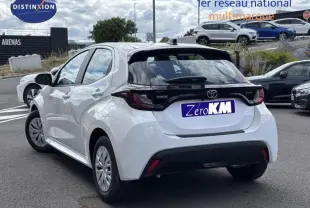 Toyota Yaris 116h Dynamic blanc vue 3/4 arrière droit avec feux arrière noirs et jantes acier.