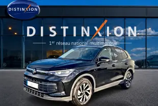 Volkswagen Tiguan noir en 3/4 avant droit, avec jantes spécifiques et calandre moderne devant un showroom Distinxion.