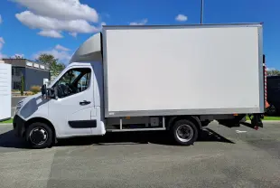 Vue de profil côté gauche d’un utilitaire blanc Nissan Interstar Châssis Cabine L3H1 avec caisse fermée sur fond urbain.