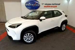 Toyota Yaris Cross blanc vue 3/4 avant droit en intérieur, avec jantes alliage et protections noires contrastées.