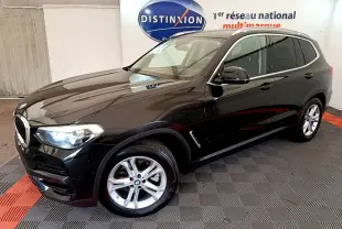 BMW X3 xDrive20d noir en 3/4 avant droit, avec jantes alliage et phares LED allumés dans un showroom.