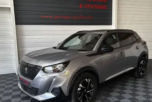 Peugeot 2008 gris clair en 3/4 avant droit, avec toit noir et jantes noires brillantes, stationné en intérieur.