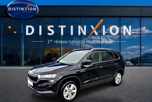 SKODA KAROQ noir 3/4 avant droit, jantes alu et barres de toit visibles devant vitrine Distinxion.