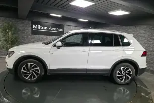 Volkswagen Tiguan blanc vu de profil côté gauche, avec jantes alliage 17 pouces et barres de toit.