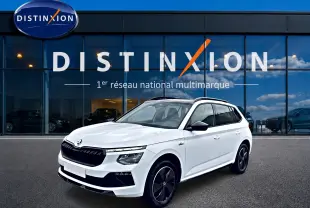 Skoda Kamiq blanc nacré en 3/4 avant droit, avec jantes noires et toit panoramique visible.