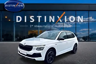 Vue 3/4 avant droite d'un Skoda Kamiq blanc nacré avec jantes noires et toit panoramique devant un showroom Distinxion.