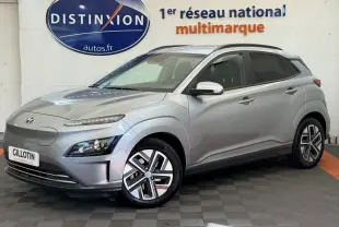 Vue 3/4 avant droite d'un Hyundai Kona électrique gris clair avec jantes spécifiques et rétroviseurs chromés.
