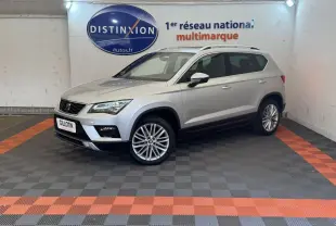 SEAT Ateca gris clair vu en 3/4 avant droit dans un showroom avec sol à damiers gris et orange.