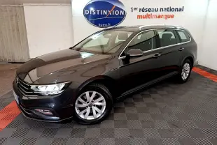 Volkswagen Passat break gris foncé vue 3/4 avant droit dans un showroom intérieur avec logo Distinxion en arrière-plan