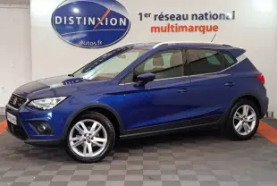 SEAT Arona bleu en vue profil côté gauche, SUV compact avec jantes alliage et barres de toit chromées.