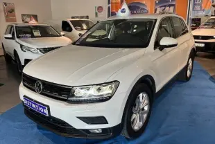 Volkswagen Tiguan blanc vu en 3/4 avant droit dans un showroom avec plaques Distinxion.
