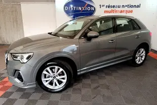 Audi Q3 gris foncé vue 3/4 avant droit, avec jantes alliage et rétroviseurs assortis dans un showroom.