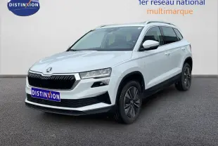 SUV Skoda Karoq blanc glacier vu en 3/4 avant droit avec calandre noire et jantes bi-ton.