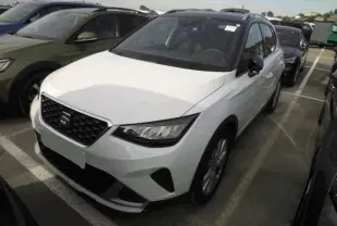 SEAT Arona blanc Nevada en 3/4 avant droit, avec calandre noire et toit noir contrasté visible.