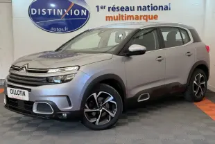 Vue 3/4 avant droit d'un Citroën C5 Aircross gris clair avec jantes noires et détails chromés, en showroom.