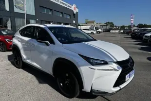 Lexus NX 300H blanc nacré en 3/4 avant droit, avec jantes noires et calandre imposante, stationné devant un garage.