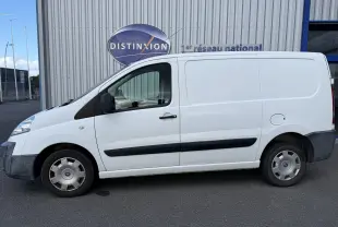 Vue de profil côté gauche d'un FIAT Scudo Fourgon blanc de 2015 avec baguettes latérales noires et jantes acier.