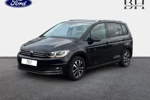 Volkswagen Touran noir intense nacré vu en 3/4 avant droit sur fond clair, avec jantes alu et barres de toit.