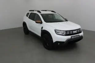 Dacia Duster 4x4 blanc en 3/4 avant droit avec rétroviseurs bronze et jantes noires dans un studio gris.