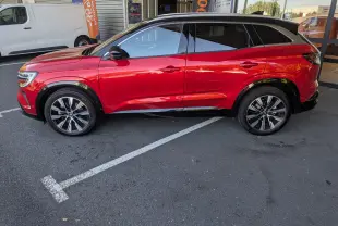Profil côté gauche du Renault Austral rouge Flamme 2025 avec toit panoramique et jantes bi-ton.
