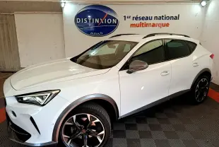 Vue 3/4 avant droite d'un CUPRA Formentor blanc avec jantes noires et détails gris métallisé en intérieur showroom.